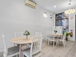 a dining room with two tables and white chairs at Lillou Hostels in Sydney