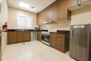 a large kitchen with wooden cabinets and stainless steel appliances at Elegant 2BR near Palm Jumeirah - 6 Min Drive in Dubai