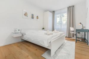 a white bedroom with a white bed and a desk at Bratislava Touch 2 BR Apt in Bratislava