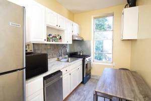 a kitchen with white cabinets and a wooden table at Tuk Ahoy - Emerald Suite 3C with Shared Spaces in Brooklyn