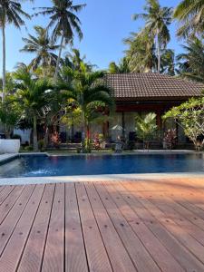 a swimming pool with a wooden deck in front of a house at Red island villas in Banyuwangi