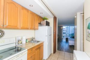 eine Küche mit Holzschränken und einem weißen Kühlschrank in der Unterkunft Ilikai Marina 1381 City View Studio in Honolulu