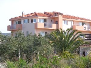 a building on top of a hill with trees at Villa Palas Apartments 2 in Rogoznica