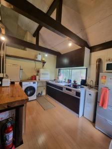 a kitchen with white appliances and a wooden floor at Bears House in Furano