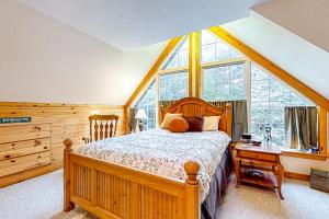 um quarto com uma cama de madeira e uma grande janela em Sugarloaf Chalet em Carrabassett