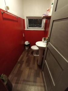 Baño rojo con lavabo y aseo en Hospedaje Santa Maria y POP, en Osorno