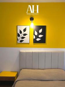 a bedroom with a bed and a yellow wall with pictures at American Hoteles in Villa Carlos Paz