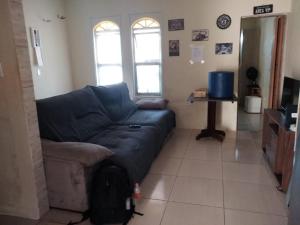 un soggiorno con un divano blu e due finestre di Casa da San a Mongaguá