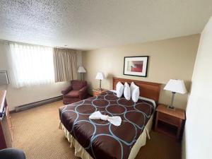 ein Hotelzimmer mit einem großen Bett und einem Stuhl in der Unterkunft Super 8 by Wyndham Williston ND in Williston