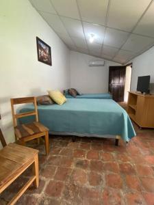 a bedroom with a blue bed and a chair at Casa Colonial in Suchitoto