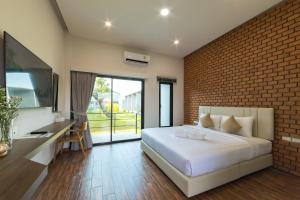 a bedroom with a white bed and a brick wall at Destino Hotel Surin 