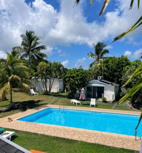 uma piscina com casa e palmeiras em Résidence Naturelle pour Naturistes em Le Moule