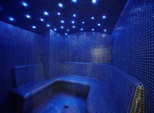 a blue bathroom with a tub with lights on it at Occidental Faro in Faro