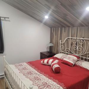 a bedroom with a red and white bed with pillows at Le Jasmin chalet complet Rivière Kayak Nature in Saint-Paulin