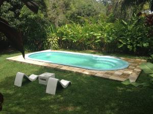 a small swimming pool in the grass with two benches at Chalé das Helicôneas - Suítes in Guaramiranga