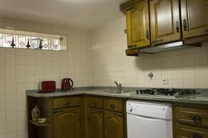 a kitchen with wooden cabinets and a white dishwasher at Casa De Santa Comba in Cabeceiras de Basto