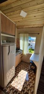 a small kitchen with a refrigerator and a window at Pousada Campus Rosa in Praia do Rosa
