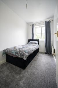 a bedroom with a large bed with a window at Maidstone villa 3bedroom free sports channels park in Maidstone