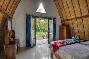 a bedroom with a bed and a large sliding glass door at Puri Garden Penida in Nusa Penida