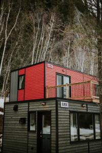 una casa roja y negra con terraza en Les Microchalets d'Édouard, en L'Anse-Saint-Jean