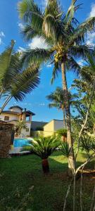 a palm tree next to a house with a swimming pool at Morada BEACHE HOUSE 515 in Bertioga
