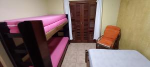 a small room with pink bunk beds and a chair at Morada BEACHE HOUSE 515 in Bertioga