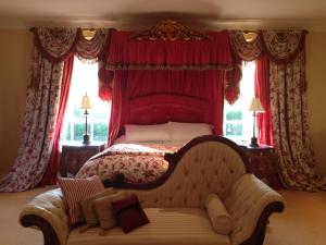 a bedroom with a bed with a couch and windows at Westbrook Country House in Castlebar