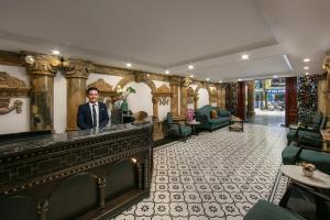a man in a suit standing behind a bar in a lobby at Media Central Hotel & Spa in Hanoi