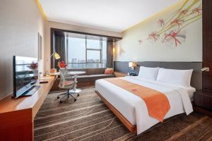 成都市にあるHilton Garden Inn Chengdu Huayangのベッド、デスク、テレビが備わるホテルルームです。