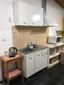 a kitchen with white cabinets and a sink and a microwave at Ruta del vino Alojamientos in Maipú +5 photos