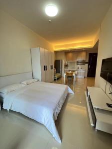 a bedroom with a large white bed and a kitchen at Seaman Light Luxury Apartment in Zhongshan