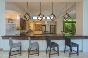 a kitchen with a large counter with chairs at it at Villa Kaira Estate in Canggu