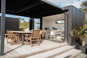 a kitchen and dining room of a house with a table and chairs at Aotearoa Surf Eco Pods in Te Arai