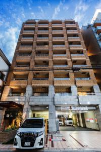 une camionnette blanche garée devant un bâtiment dans l'établissement Apartment Hotel 11 Shinsaibashi AMEMURA, à Osaka