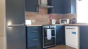 a kitchen with blue cabinets and a stove top oven at Carvetii - Clark House - Spacious ground floor flat in Rosyth