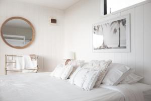 a white bed with white pillows and a mirror at Aotearoa Surf Eco Pods in Te Arai