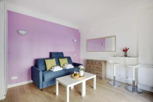Cozy studio next to Gare de l'Est في باريس: غرفة معيشة مع أريكة زرقاء وطاولة