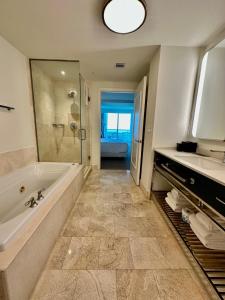 een badkamer met een bad, een wastafel en een spiegel bij Fontainebleau Miami Beach,Tresor in Miami Beach