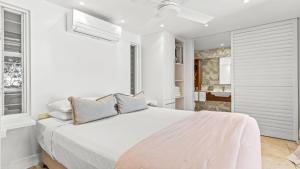 a white bedroom with a large bed and a bathroom at Watermark at Wategos Residence 3 Bedroom in Byron Bay