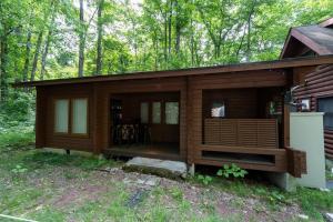 een hut in het bos met een veranda bij S-villa Karuizawa wood creek in Tsumagoi