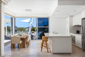 a kitchen with white cabinets and a table with chairs at Waterview Penthouse - Cote D'Azur Resort, Nelson Bay in Nelson Bay