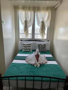 a bed in a bedroom with a window and a bed with a bedspread at Green Residences Stays by PBYY in Manila