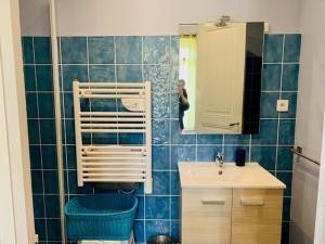 una persona que toma una foto de un baño de azulejos azules en Appartement Amélie-les-Bains-Palalda, 2 pièces, 2 personnes - FR-1-703-153, en Amélie-les-Bains-Palalda