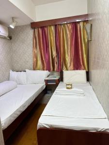 two beds in a small room with a window at Piaget guest house in Hong Kong