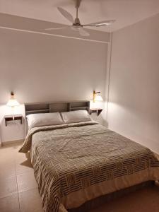 een slaapkamer met een bed en een plafondventilator bij La Estadía in Puerto Madryn