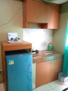 a kitchen with a blue refrigerator and a sink at Apartemen Green Lake View Ciputat by My Rooms in Pondokcabe Hilir