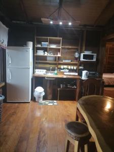 eine Küche mit einem weißen Kühlschrank und einem Tisch in der Unterkunft Rancho de Moncho in Bijagua