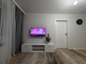 una sala de estar blanca con TV en la pared en Auezov Apartment, en Almaty