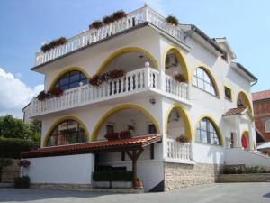 Un grand bâtiment blanc avec des fleurs sur les balcons dans l'établissement Villa Flora, à Malinska