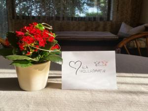 a vase of red flowers and a sign on a table at Ferienwohnungen Karle in Künzelsau